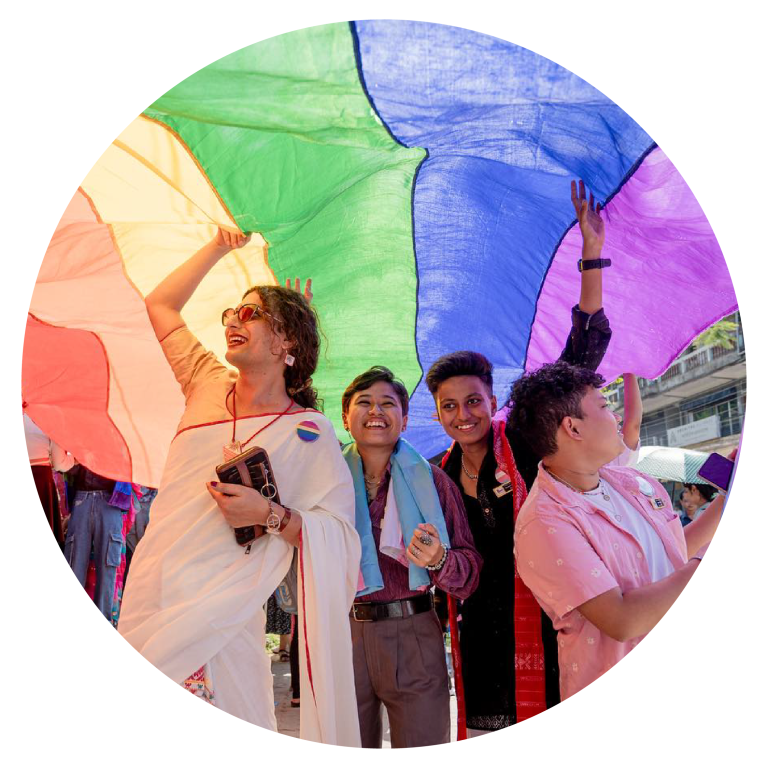 Four people stand under a pride flag in Dibrugarh, India