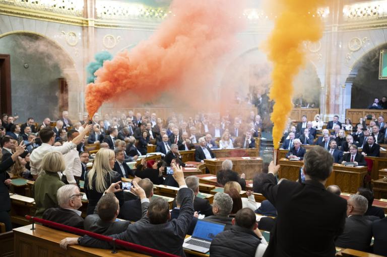 Hungary's legislative body meeting with people shooting colorful smoke