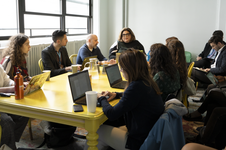 Global Intersex Program roundtable. Advocates sit around a yellow table with computers to discuss the rights of Intersex people internationally