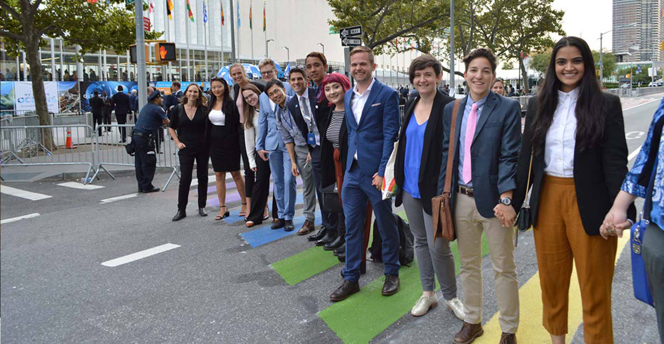activists holding hands in front of the UN HQ in new york on a rainbow cross walk